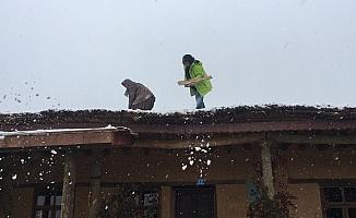 Sanatçılar kerpiç evlerin toprak damında kar küredi